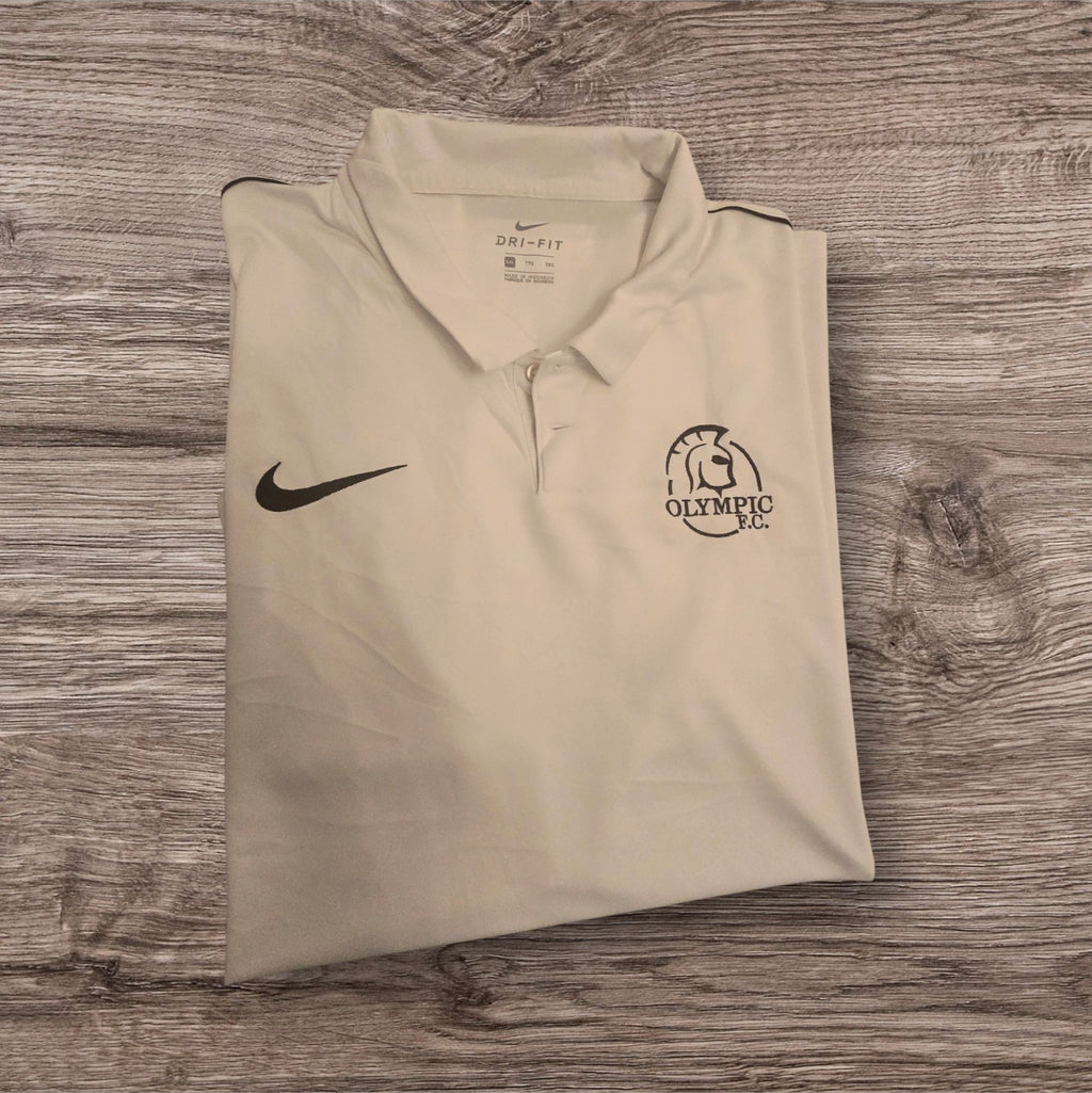 Polo tecnica bianca Ottoman Kumus Nike Dri-FIT con logo e stemma Olympic F.C. su sfondo in legno
