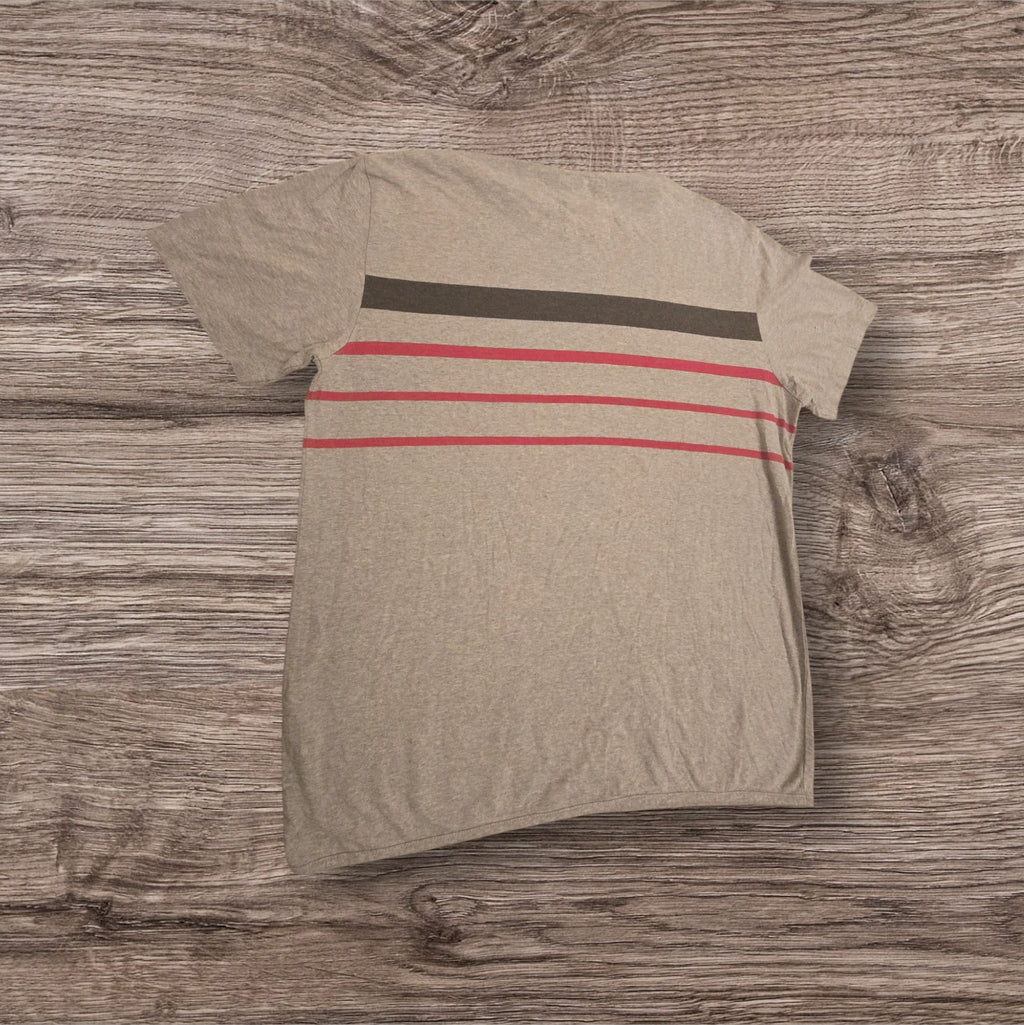 T-shirt Ottoman Kumus in cotone grigio mélange con righe orizzontali nere e rosse sul petto su sfondo in legno