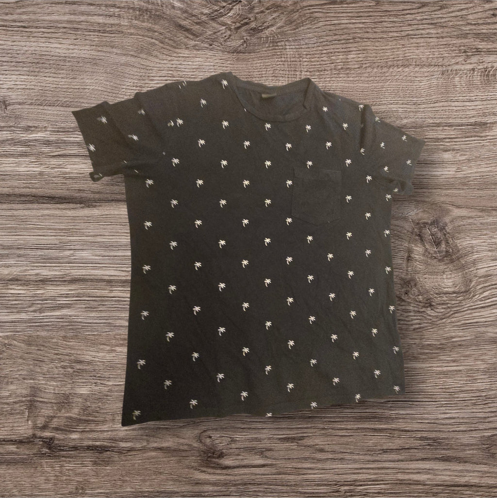 T-shirt Ottoman Kumus nera in cotone con stampa di palme bianche e taschino sul petto, stile casual estivo.
