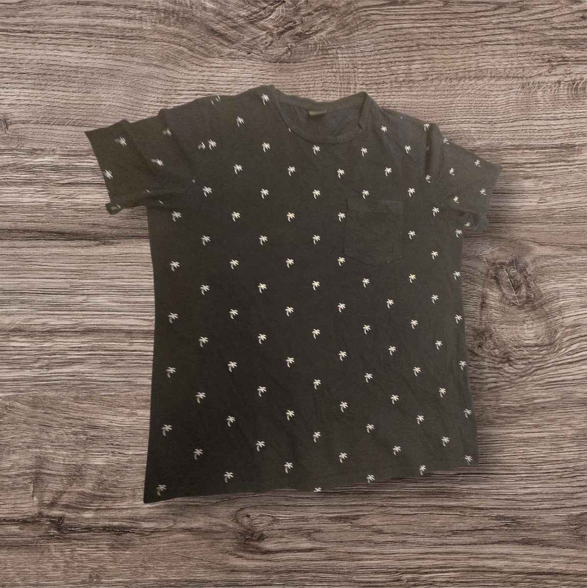 T-shirt Ottoman Kumus nera in cotone con stampa di palme bianche e taschino sul petto, stile casual estivo.