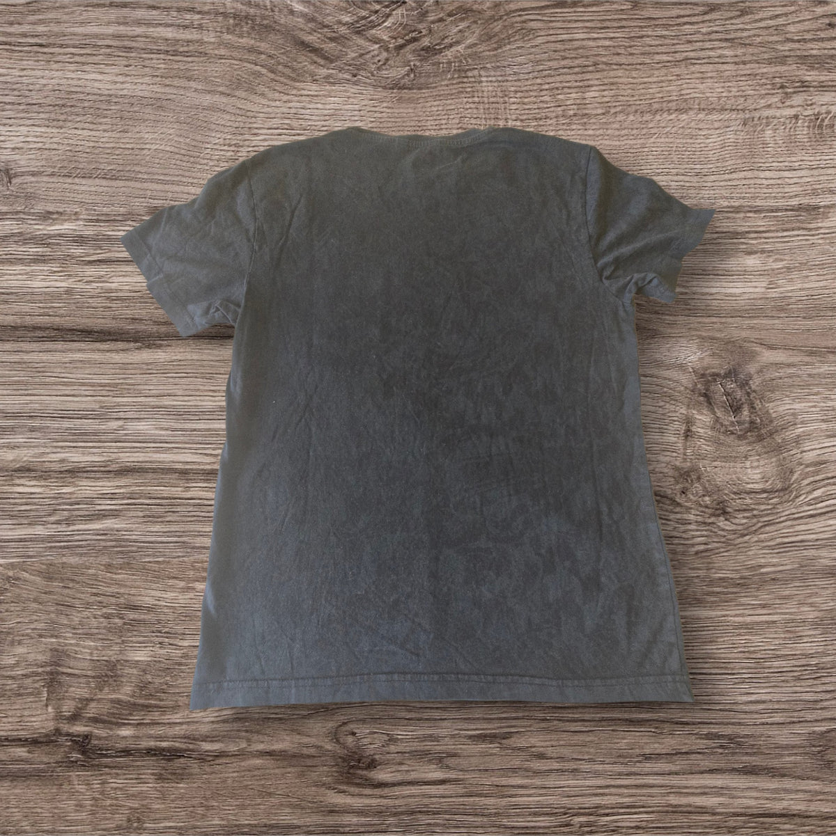 T-shirt nera in cotone Ottoman Kumus vista posteriore su sfondo in legno