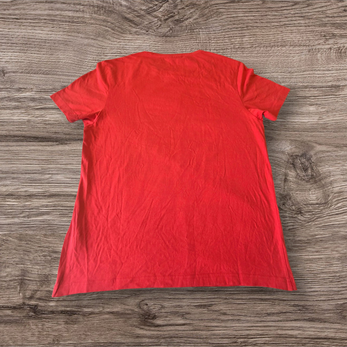 Retro della t-shirt rossa a maniche corte Ottoman Kumus in cotone morbido con girocollo su sfondo in legno