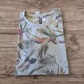 T-shirt Ottoman Kumus grigio mélange con stampa tropicale di pappagalli e taschino sul petto, piegata su legno.